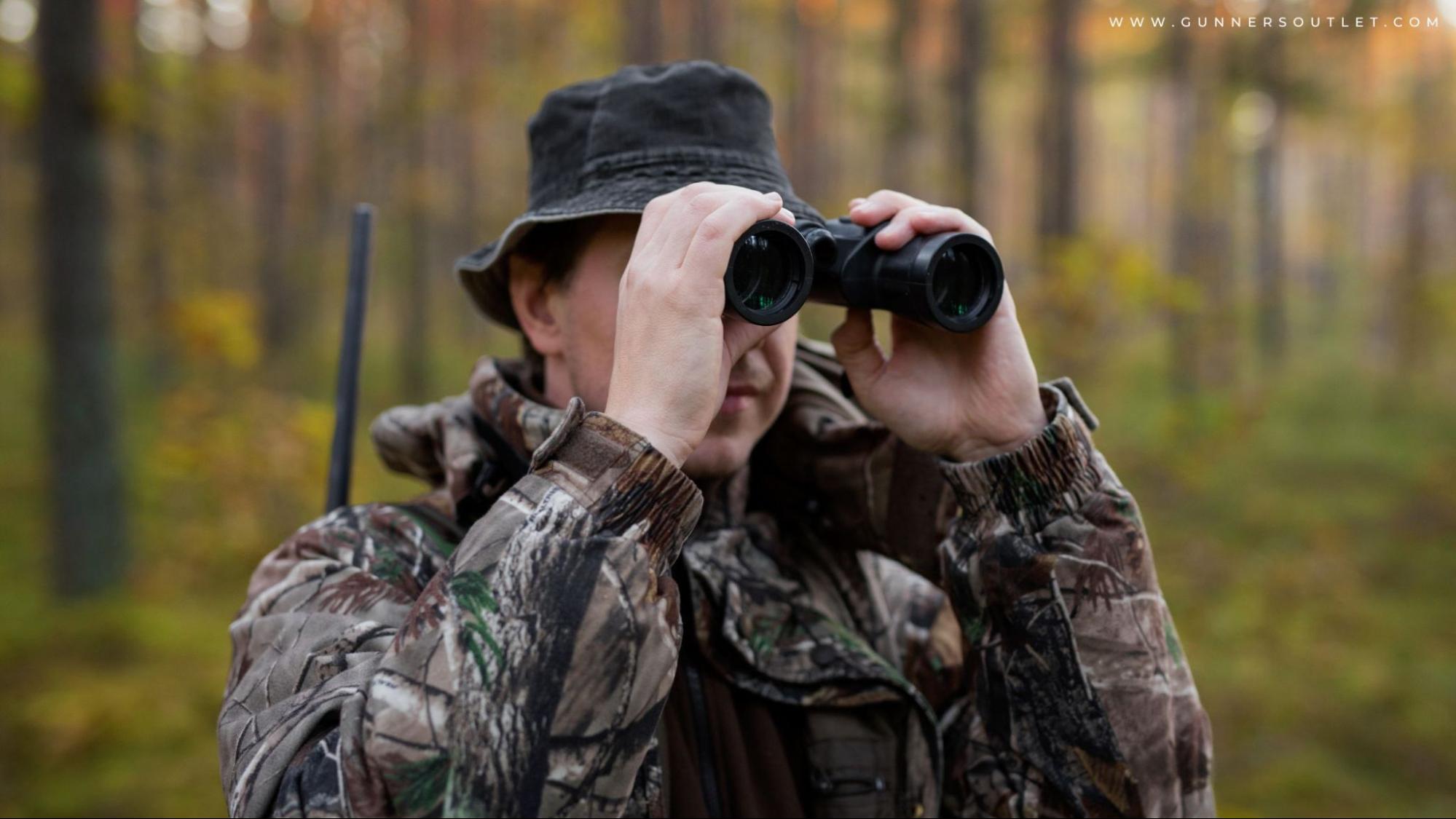 man looking through binoculars in the forest